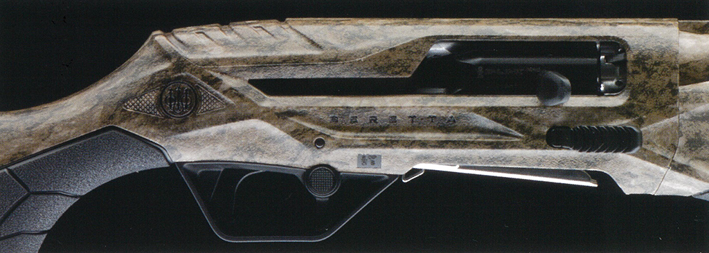 Mossy Oak Bottomland – f-range 東京表参道の銃砲店 Camouflaged futuristic rifle laid on a dark background, showing grip, trigger area, and metallic components to the right.